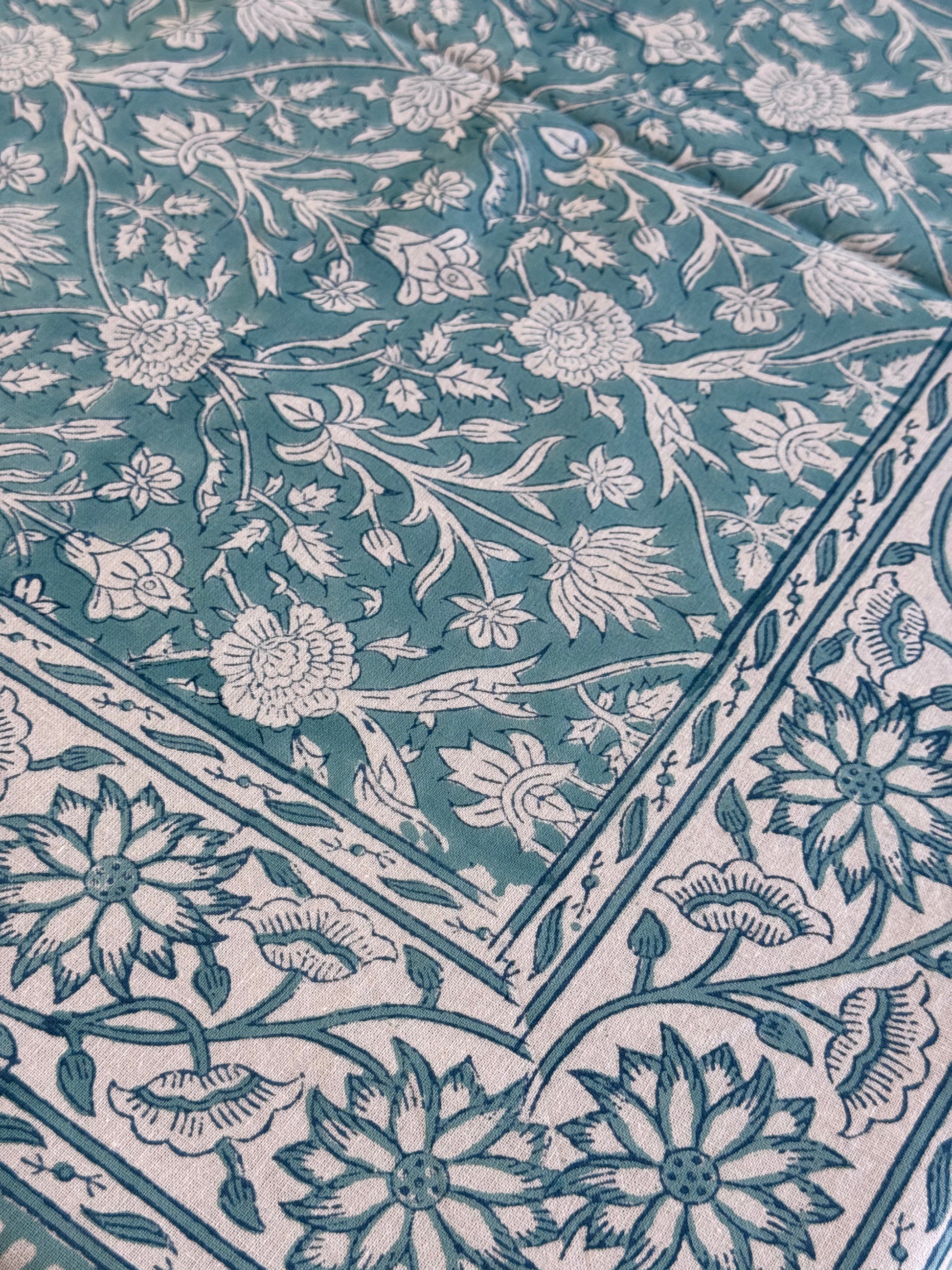 Zoom sur les motifs fleuris et la bordure décorative de la nappe PADMA bleu,  imprimée à la main en Inde.