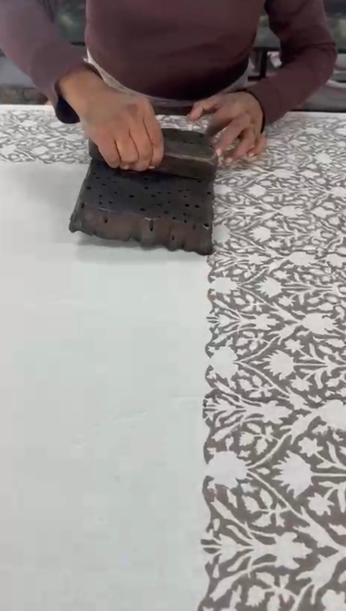 gros plan sur la technique d'impression block print ou l'on voit nettement en gros plan un homme appliquer la couleur avec son tampons de bois 