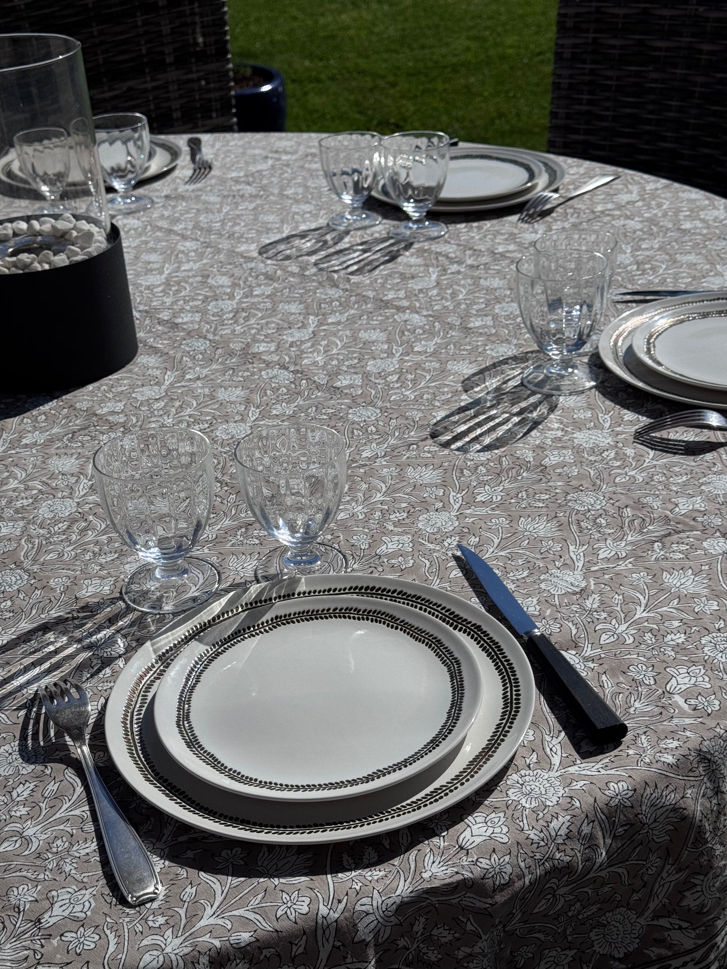 Nappe ronde Dehli beige dressée en extérieur avec de la vaisselle et des verres en cristal