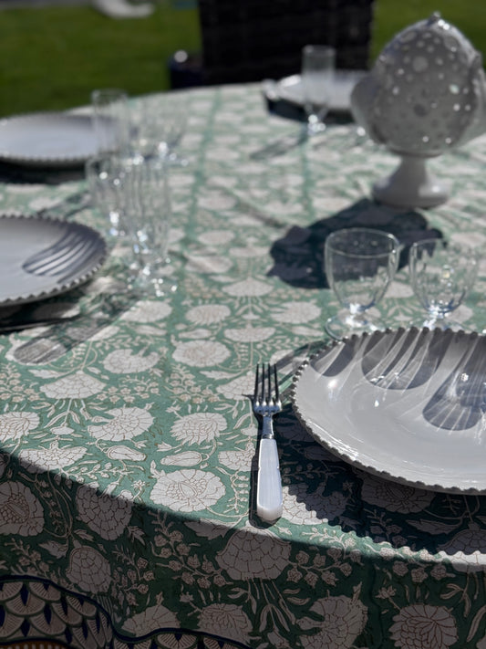 Gros plan sur la nappe Jaipur dressée sur une table ronde en extérieur avec de la jolie vaisselle blanche 