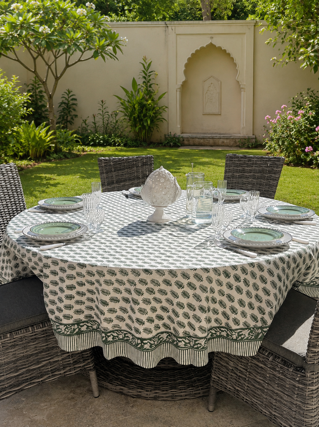 Grande nappe ronde PAVANA verte présentée sur une jolie table en extérieur dans un jardin verdoyant