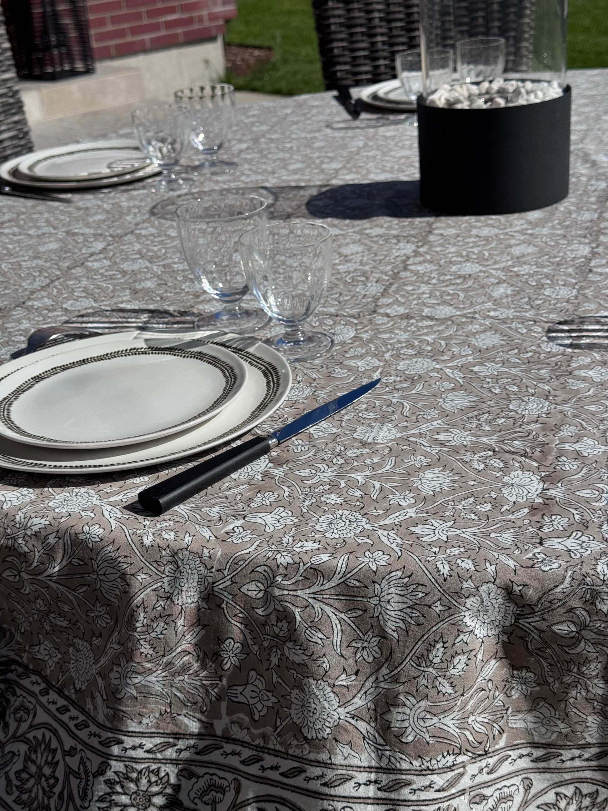 Nappe Dehli en coton beige sur une jolie table ronde dressée avec de la vaisselle et verres en cristal