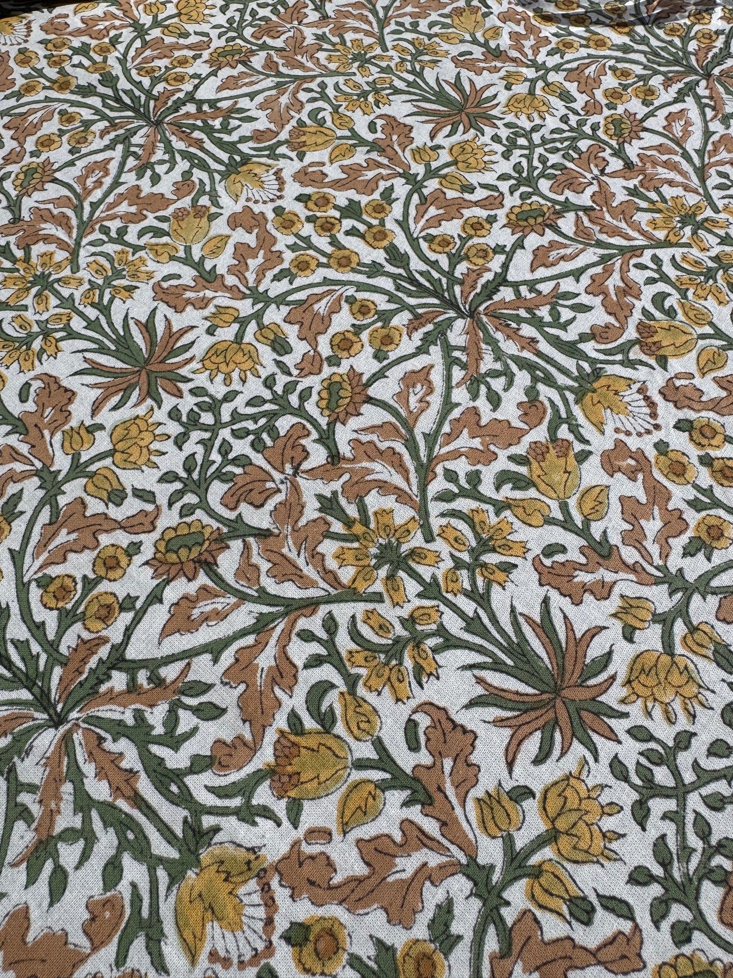 Zoom sur les motifs floraux de la nappe Jaipur avec gros plan sur ses nuances de jaune, terra cotta, vert et beige