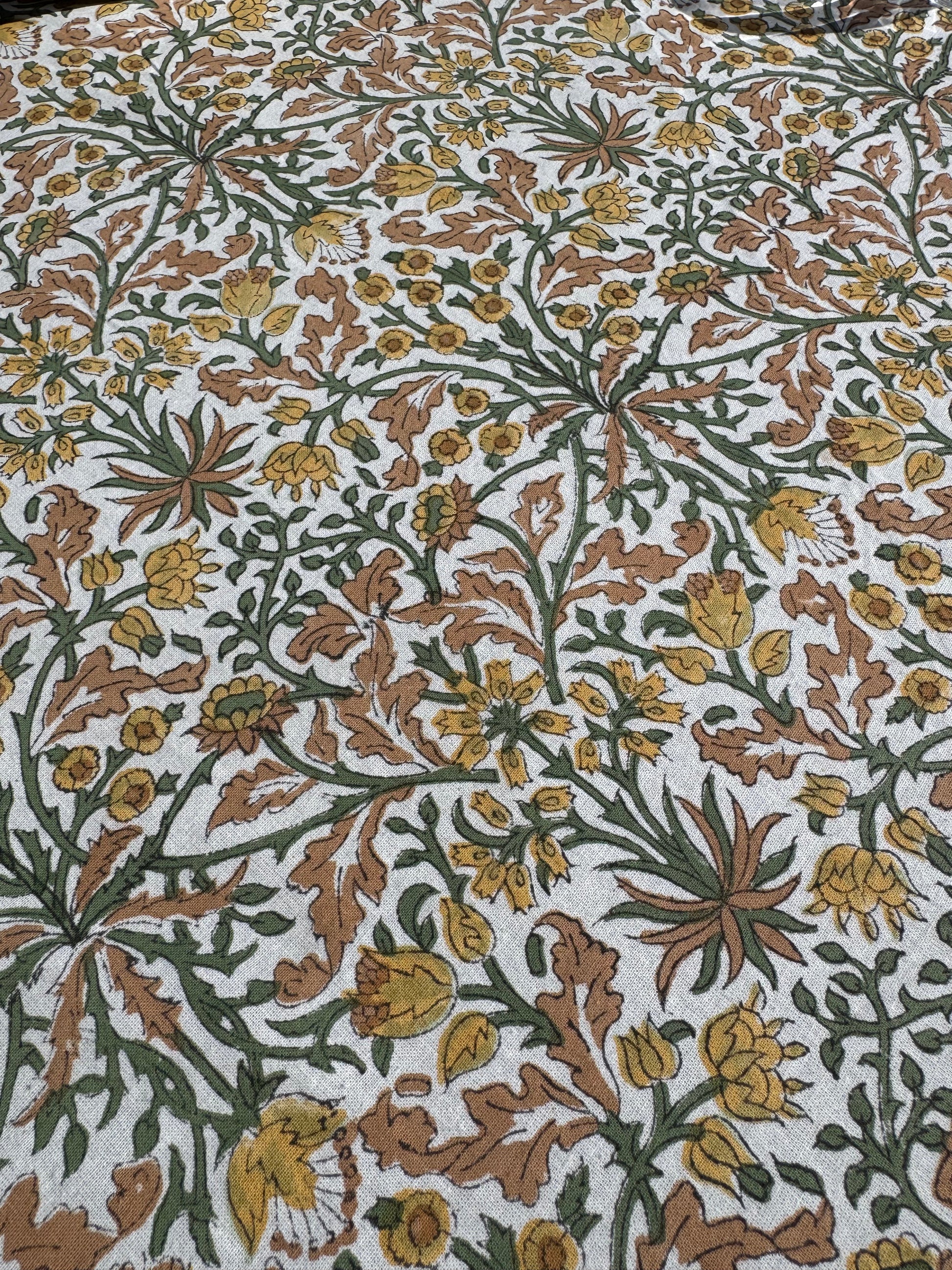 Zoom sur les motifs floraux de la nappe Jaipur avec gros plan sur ses nuances de jaune, terra cotta, vert et beige